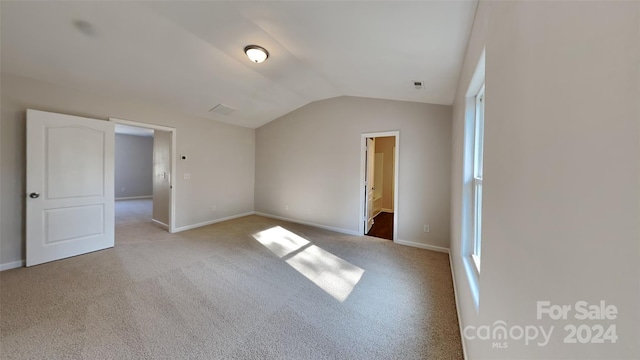 carpeted empty room featuring vaulted ceiling