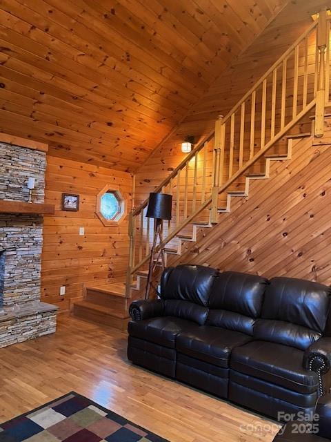 living room with hardwood / wood-style flooring, wooden walls, wooden ceiling, and vaulted ceiling