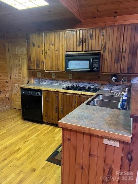 kitchen featuring wood walls, sink, wood ceiling, black appliances, and light hardwood / wood-style flooring