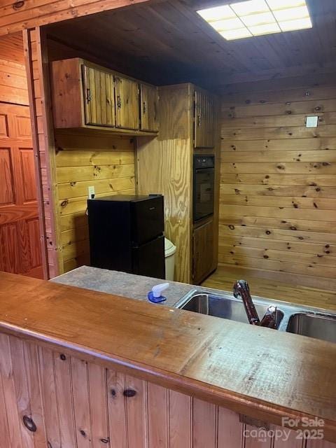 kitchen featuring wood ceiling, wooden walls, and black appliances