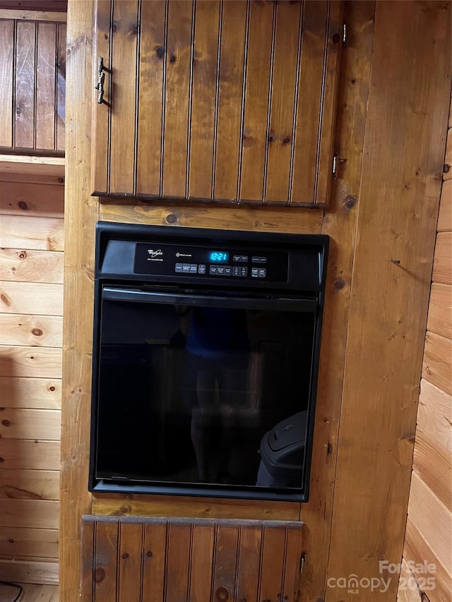 details with oven, dark brown cabinets, and wood walls