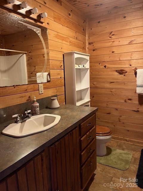 bathroom featuring vanity, toilet, walk in shower, and wood walls