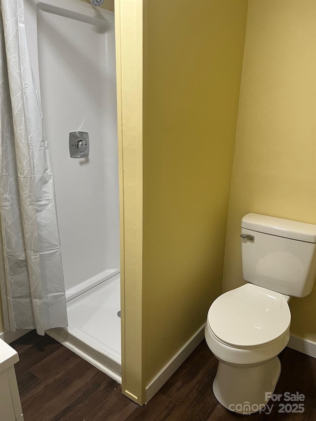 bathroom with hardwood / wood-style floors, toilet, and a shower with shower curtain