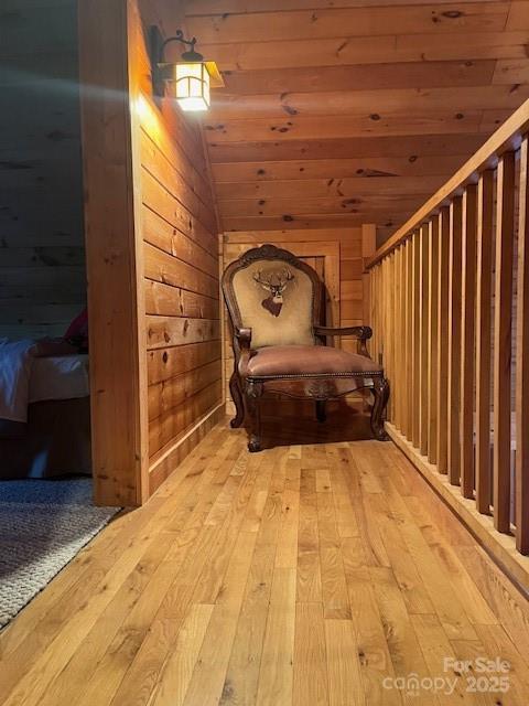 hallway with vaulted ceiling, wood ceiling, wooden walls, and light hardwood / wood-style floors