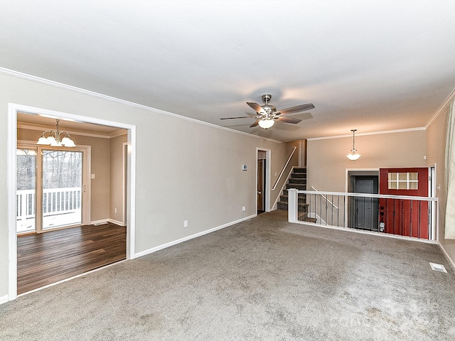 unfurnished living room featuring carpet, ceiling fan with notable chandelier, and ornamental molding