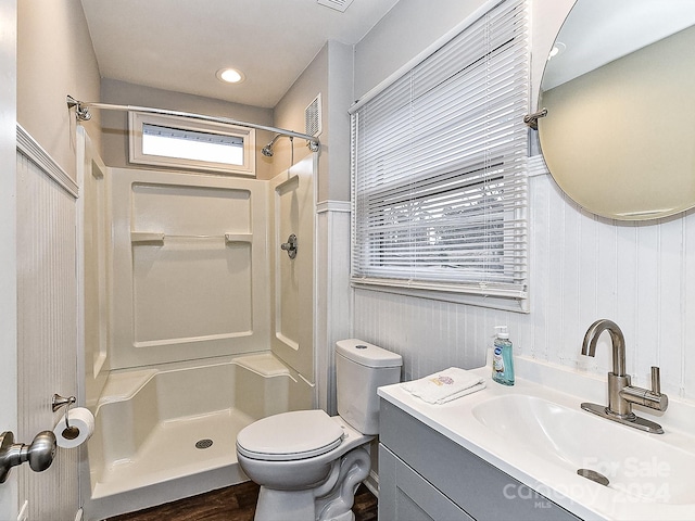 bathroom with a shower, vanity, toilet, and wood walls