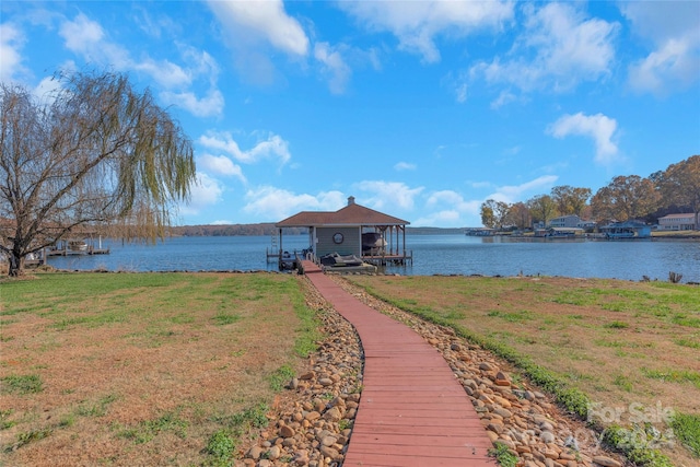 view of dock with a lawn and a water view