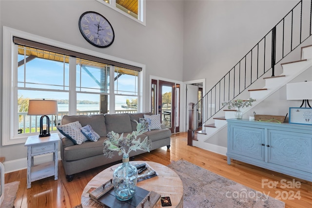 living room with a water view, wood-type flooring, and a towering ceiling