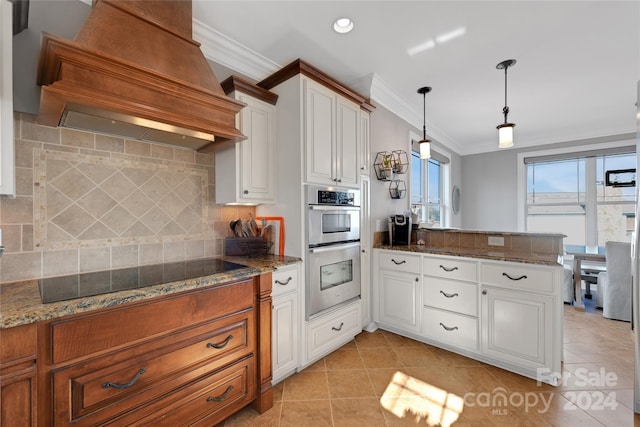 kitchen featuring premium range hood, black electric cooktop, tasteful backsplash, decorative light fixtures, and white cabinetry