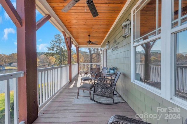 wooden deck with ceiling fan and a water view