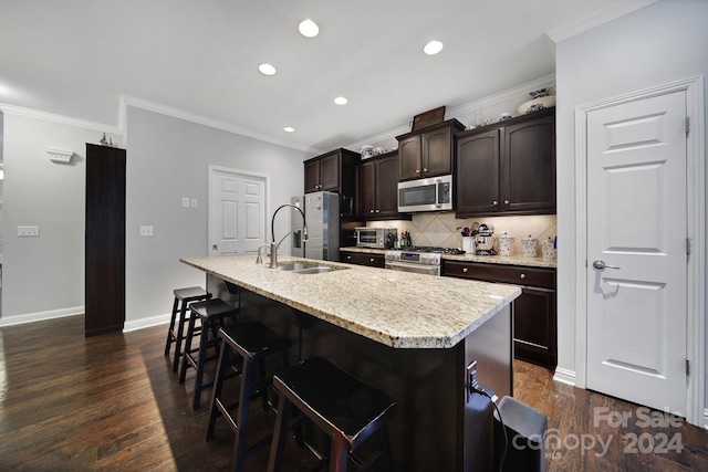 kitchen with appliances with stainless steel finishes, dark brown cabinets, dark wood-type flooring, a center island with sink, and a breakfast bar area