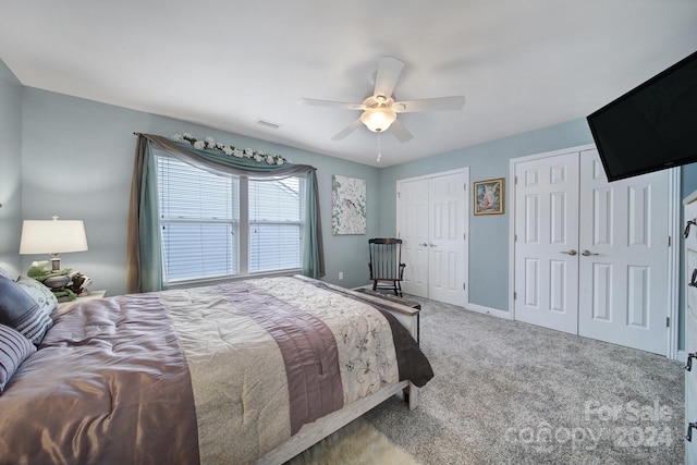 bedroom with carpet flooring, ceiling fan, and multiple closets