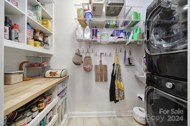 laundry room featuring light tile patterned floors and stacked washer and dryer