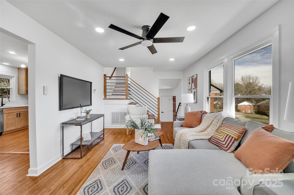 living room featuring stairs, light wood finished floors, visible vents, and recessed lighting