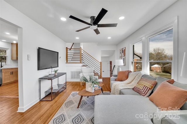 living room featuring stairs, light wood finished floors, visible vents, and recessed lighting