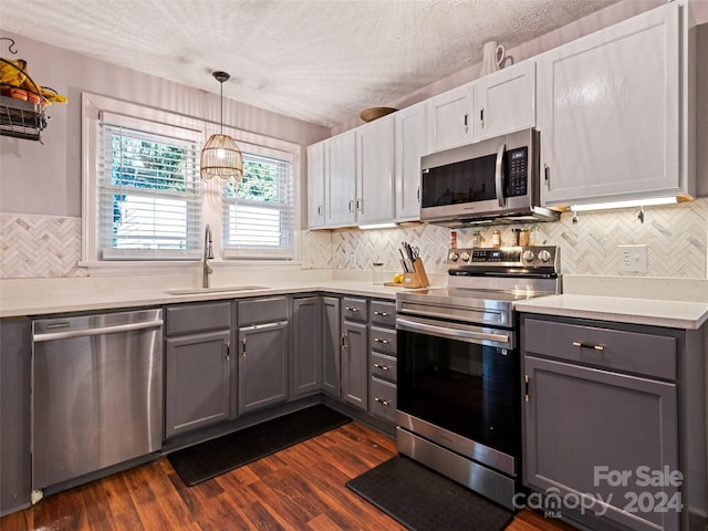 kitchen with gray cabinetry, sink, appliances with stainless steel finishes, and dark wood-type flooring