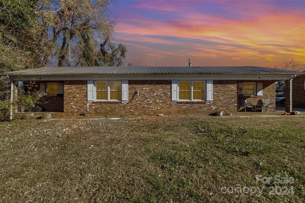 back house at dusk with a lawn