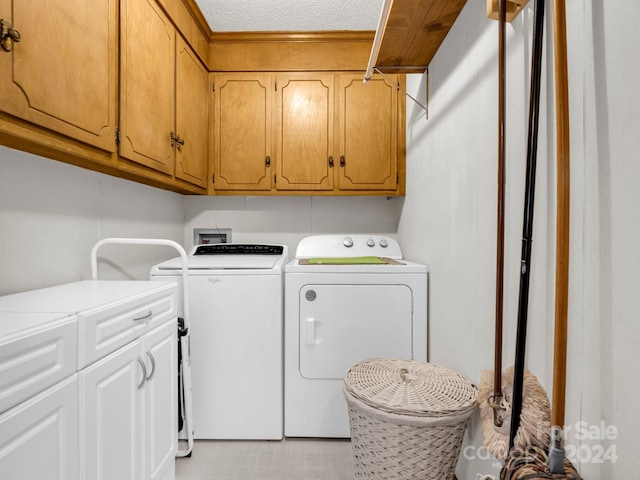 washroom featuring cabinets, a textured ceiling, and washing machine and clothes dryer