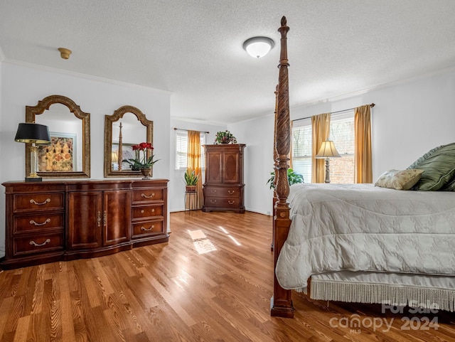 bedroom featuring a textured ceiling, light hardwood / wood-style flooring, and crown molding