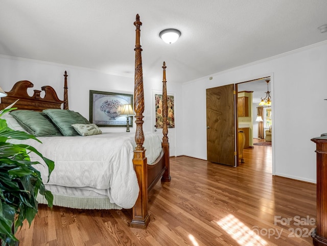 bedroom with hardwood / wood-style floors, a textured ceiling, and ornamental molding