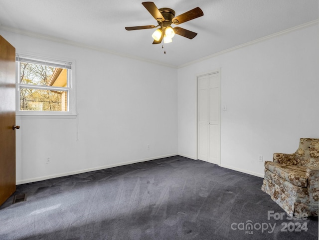 spare room with ceiling fan, dark carpet, and crown molding