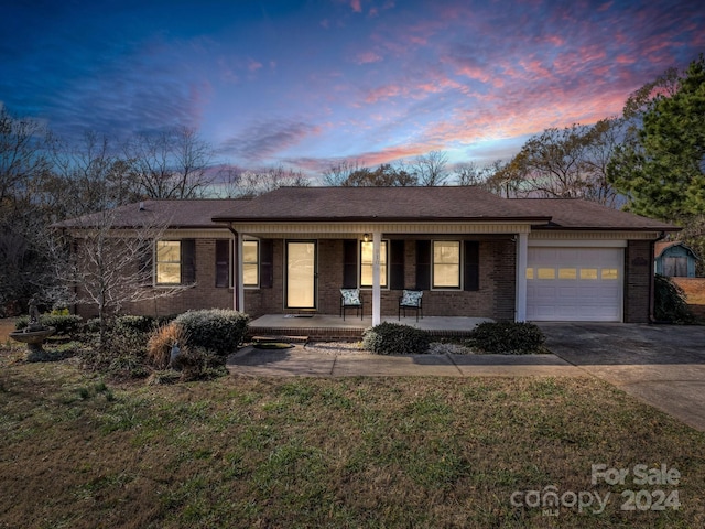 single story home featuring a lawn, a porch, and a garage