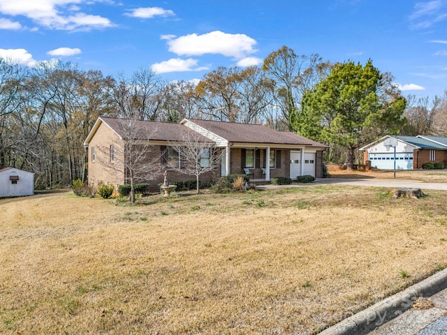 ranch-style home with a front yard, a porch, a shed, and a garage