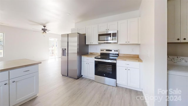 kitchen with washer / dryer, appliances with stainless steel finishes, white cabinets, and butcher block counters