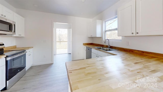 kitchen with appliances with stainless steel finishes, light hardwood / wood-style flooring, white cabinetry, and sink