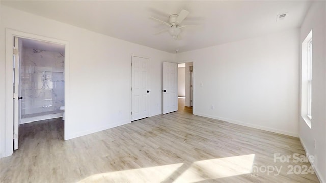 unfurnished bedroom featuring a closet, ensuite bath, ceiling fan, and light hardwood / wood-style flooring