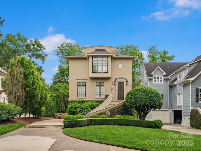 view of front of home with concrete driveway, an attached garage, a front yard, and stucco siding