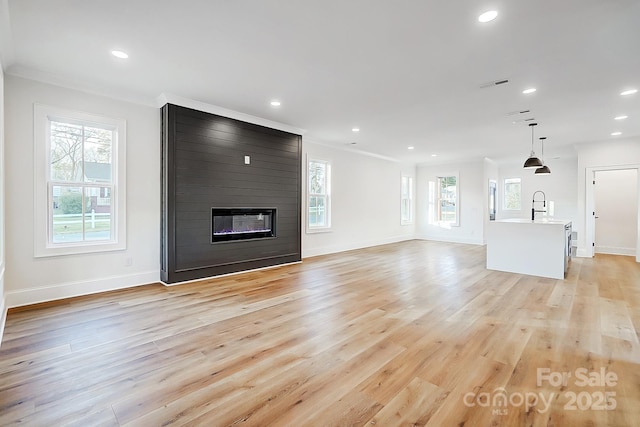 unfurnished living room featuring a large fireplace, light hardwood / wood-style floors, and crown molding