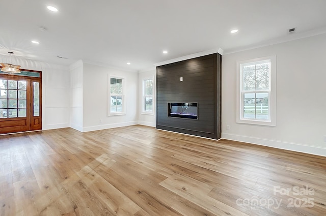 unfurnished living room with a healthy amount of sunlight, crown molding, a fireplace, and light hardwood / wood-style flooring