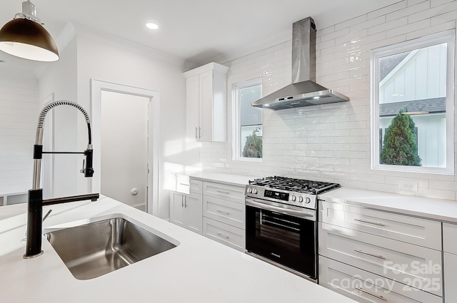 kitchen with gas range, sink, wall chimney range hood, tasteful backsplash, and white cabinets