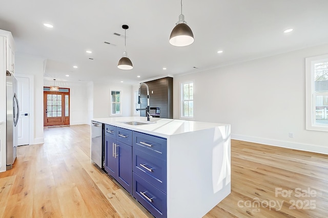 kitchen featuring a center island with sink, white cabinets, hanging light fixtures, blue cabinetry, and appliances with stainless steel finishes