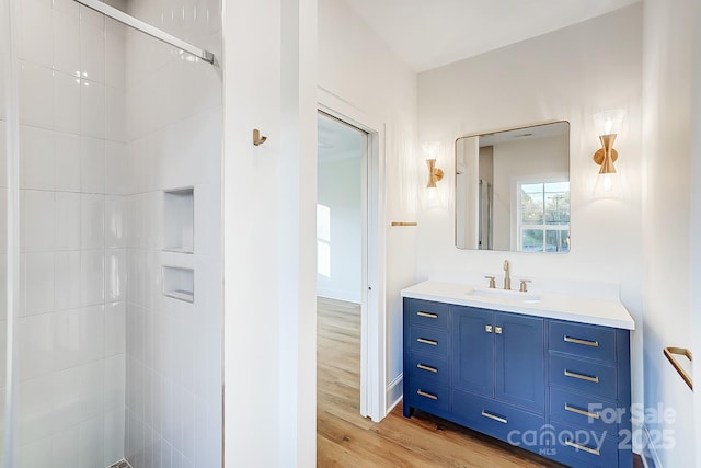 bathroom with tiled shower, hardwood / wood-style floors, and vanity