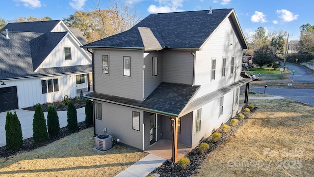 view of side of home with central AC unit and roof with shingles