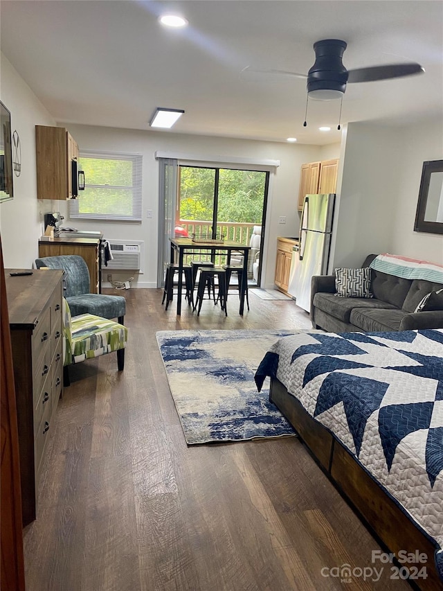 bedroom featuring stainless steel fridge, ceiling fan, wood-type flooring, and a wall mounted air conditioner