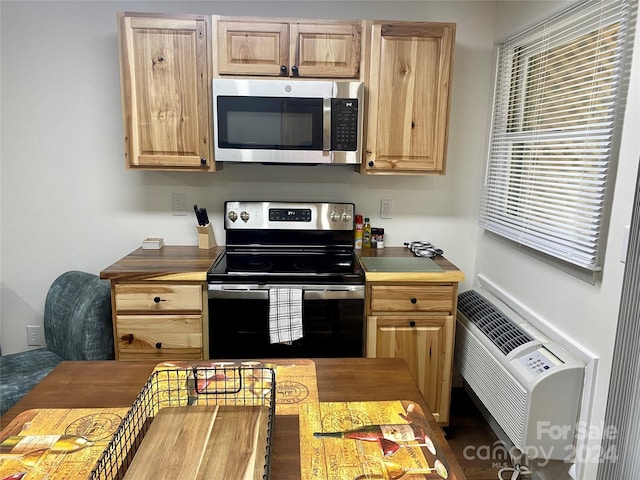 kitchen featuring light brown cabinets, stainless steel appliances, and a wall unit AC