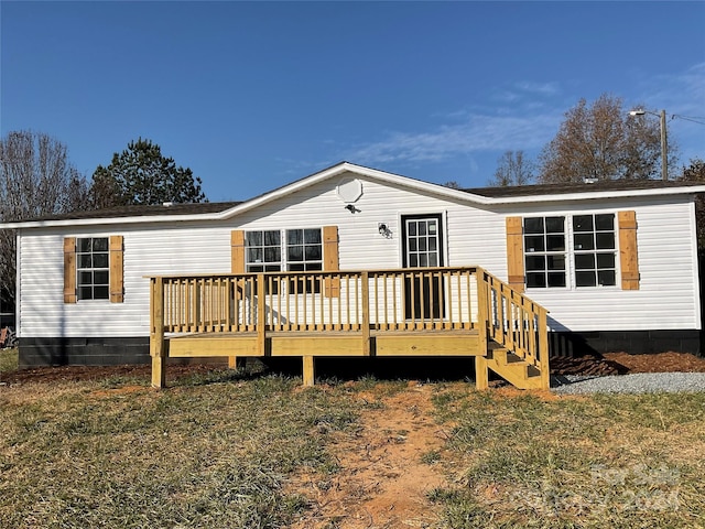 rear view of house featuring a wooden deck and a yard