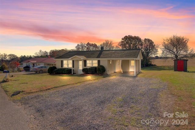 ranch-style house with a yard, a carport, and a storage unit