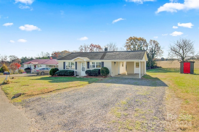 ranch-style house featuring a storage shed, a front yard, and a carport