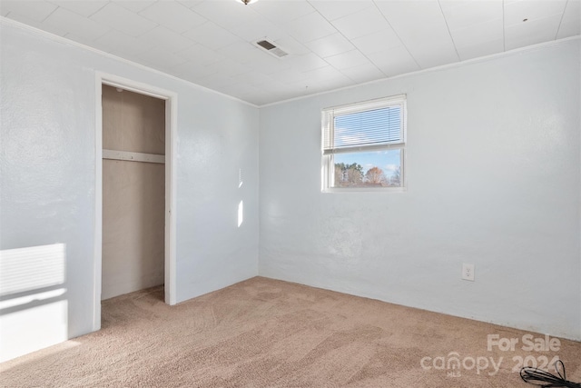 unfurnished bedroom with light colored carpet, ornamental molding, and a closet