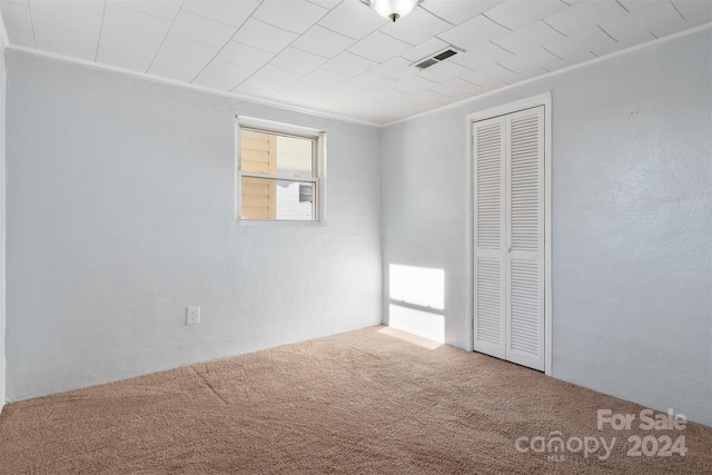 unfurnished bedroom featuring carpet flooring, a closet, and ornamental molding