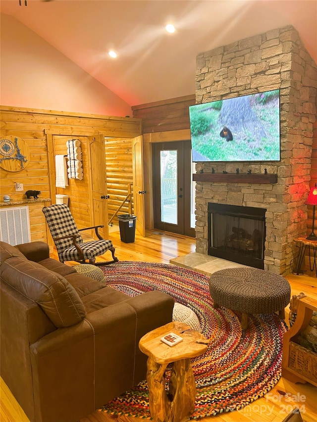 living room with a fireplace, hardwood / wood-style floors, wooden walls, and lofted ceiling