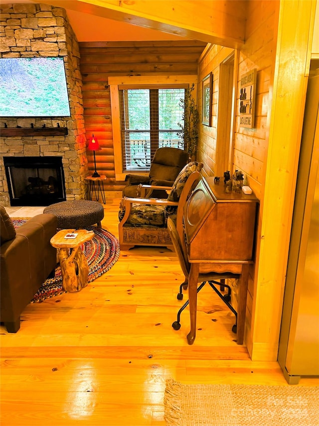 living room featuring log walls, light wood-type flooring, and a stone fireplace