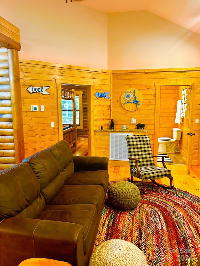 living room featuring hardwood / wood-style flooring, high vaulted ceiling, and wood walls