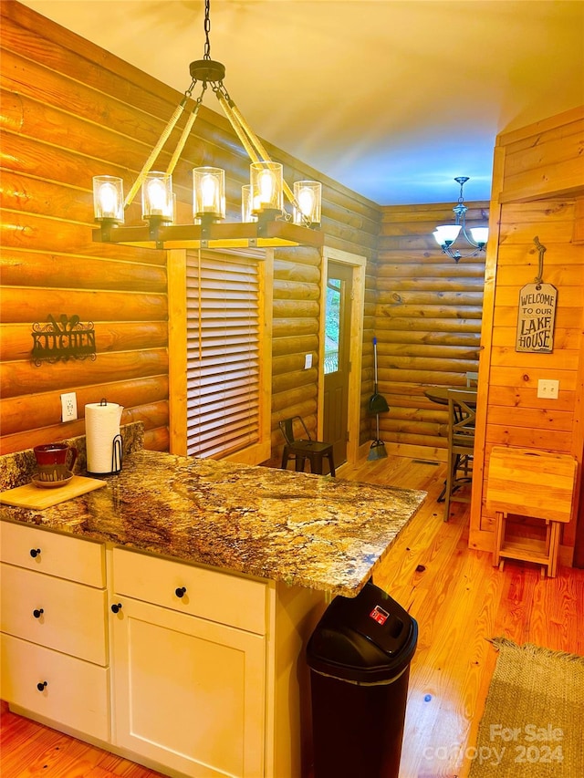 229 Seton Rd, Lake Lure, NC 28746 - kitchen featuring log walls, white cabinets, light wood-style flooring, a chandelier, and stone countertops