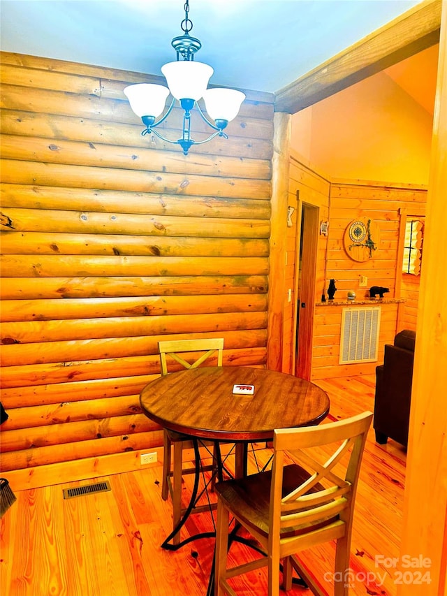 dining area with rustic walls, light hardwood / wood-style floors, lofted ceiling, and a notable chandelier