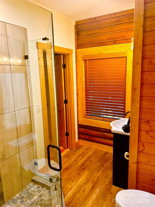 bathroom featuring wood walls, hardwood / wood-style floors, vanity, and a shower with door